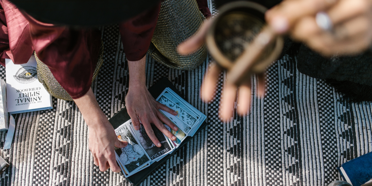 One person spreads out tarot cards while another uses a Tibetan singing bowl.