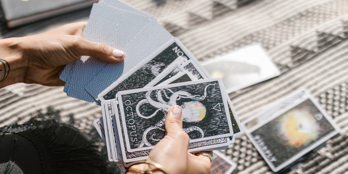 Some holds a deck of tarot card in their hands.